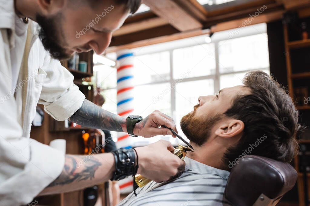 brunette bearded man near hairstylist working with comb and hair clipper
