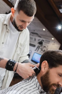 Berber dükkanındaki bulanık müşterinin saçlarını buduyor. 