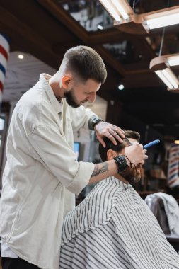 Profesyonel berber. Adamın alnını jiletle traş ediyor.
