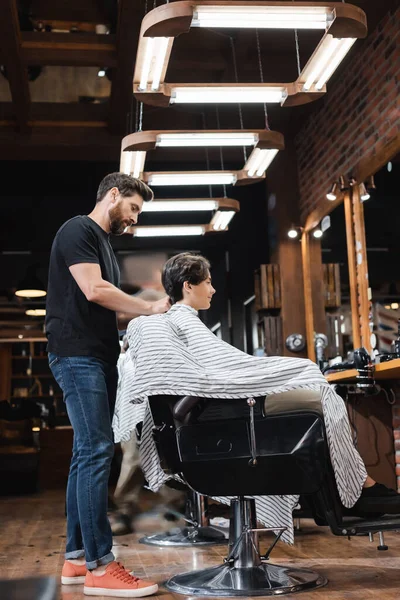 Zijaanzicht Van Bebaarde Hairstylist Dragen Cape Tiener Client Schoonheidssalon — Stockfoto