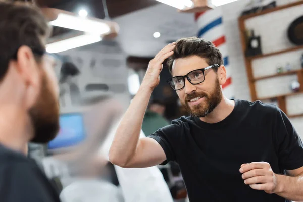 Smiling Client Eyeglasses Looking Mirror Touching Hair Barbershop — Stock Photo, Image
