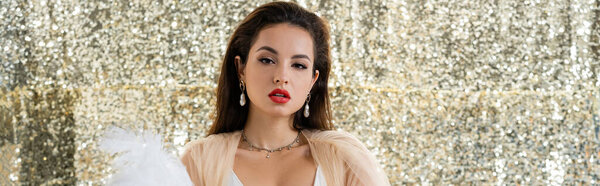 брюнетка женщина в элегантной одежде шифона глядя на камеру на блестящем серебристом фоне, баннер