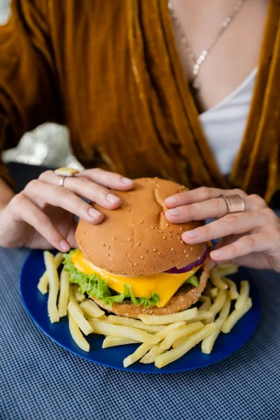 Częściowy Widok Niewyraźne Kobieta Gospodarstwa Pyszne Hamburgery Pobliżu Frytki Niebieskim — Zdjęcie stockowe