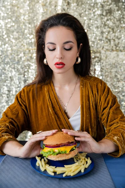 Jovem Mulher Vestido Elegante Segurando Delicioso Hambúrguer Perto Batatas Fritas — Fotografia de Stock