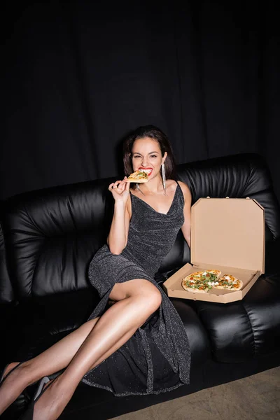 Sexy Frau Isst Leckere Pizza Während Sie Auf Ledercouch Isoliert — Stockfoto