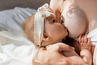 Başında fiyonkla bebek emziren bir kadın. 
