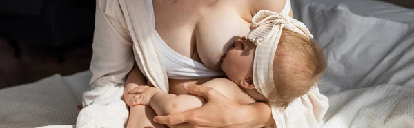 라운지에 엄마가 머리에 두르고 현수막을 두르고 아기에게 모유를 먹이고 — 스톡 사진