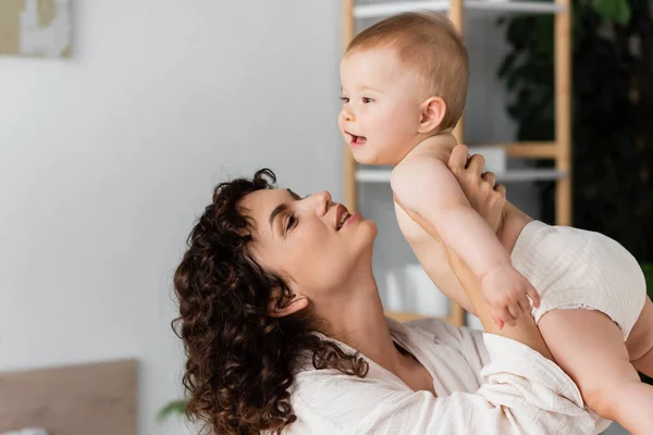 Nöjd Kvinna Med Lockigt Hår Ler Samtidigt Hålla Armar Spädbarn — Stockfoto