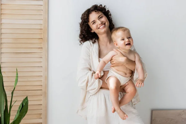 Mulher Morena Sorrindo Para Câmera Enquanto Segurava Menina Perto Tela — Fotografia de Stock