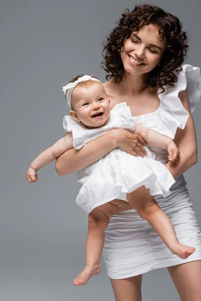 把女婴抱在头上 白色衣服与灰色隔离的女人 — 图库照片