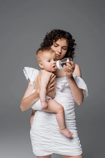 Snygg Mamma Håller Baby Flaska Och Spädbarn Dotter Isolerad Grå — Stockfoto