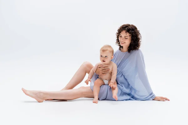 Krullende Vrouw Jurk Kijken Naar Baby Dochter Terwijl Zitten Witte — Stockfoto