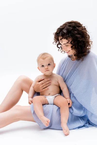 Positive Brünette Mutter Looking Baby Daughter Während Sitzen Auf Weißem — Stockfoto