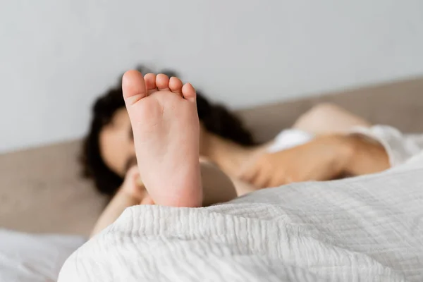 Fuß Des Kleinen Mädchens Neben Verschwommener Mutter Auf Bett — Stockfoto