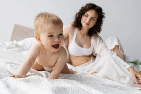Positive Infant Girl Looking Away Blurred Mother Bed Morning — Stock Photo, Image