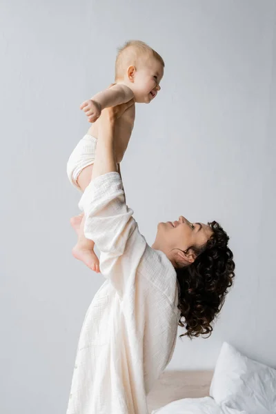 Side View Cheerful Woman Lifting Baby Daughter Bedroom — Stock Photo, Image