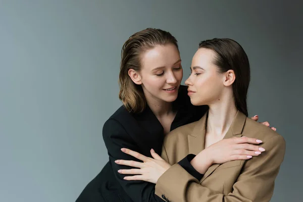 Lesbianas Sonrientes Blazers Beige Negro Abrazándose Aislados Gris — Foto de Stock