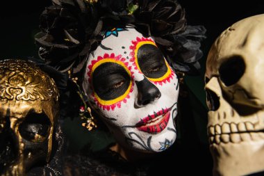 Meksikalı Noel Baba makyajlı bir kadının portresi. Siyahların izole edilmiş kafatasına bakıyor. 
