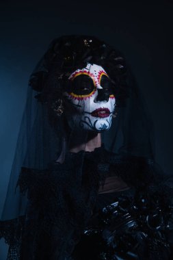 Geleneksel Meksika Catrina makyajlı kadın ve koyu mavi arka planda peçeli siyah çelenk.