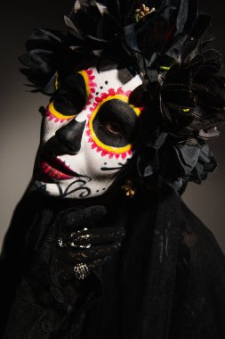 Siyah arka planda siyah çelenk ve Santa Muerte makyajlı kadın portresi