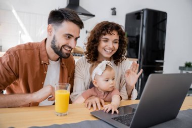 Küçük çocuklu neşeli bir aile dizüstü bilgisayarında video görüşmesi yapıyor.