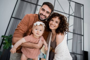 Neşeli sakallı bir babanın kucağında kızının yanında neşeli bir eş tutması.