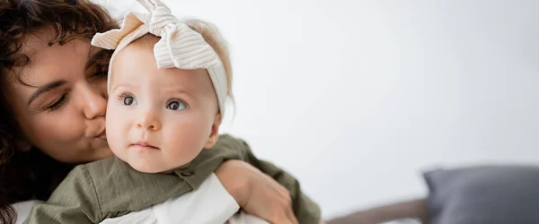 곱슬곱슬 어머니가 머리띠를 두르고 아기의 껴안고 맞추는 현수막 — 스톡 사진