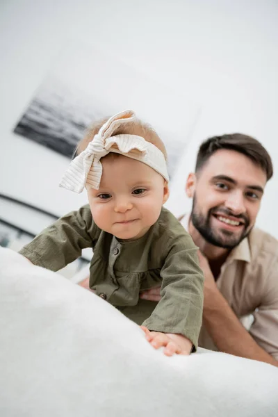 Šťastný Vousatý Otec Při Pohledu Kameru Zatímco Dítě Plazí Posteli — Stock fotografie