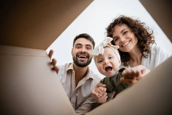 Mutlu Ebeveynler Karton Kutunun Içine Bakan Heyecanlı Bir Kız Çocuğu — Stok fotoğraf