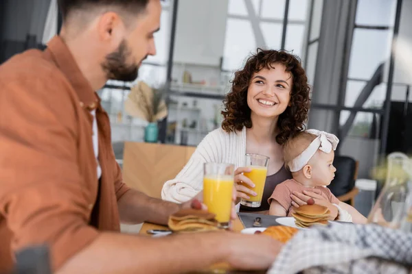 Lycklig Kvinna Håller Spädbarn Dotter Och Tittar Skäggig Make Frukost — Stockfoto