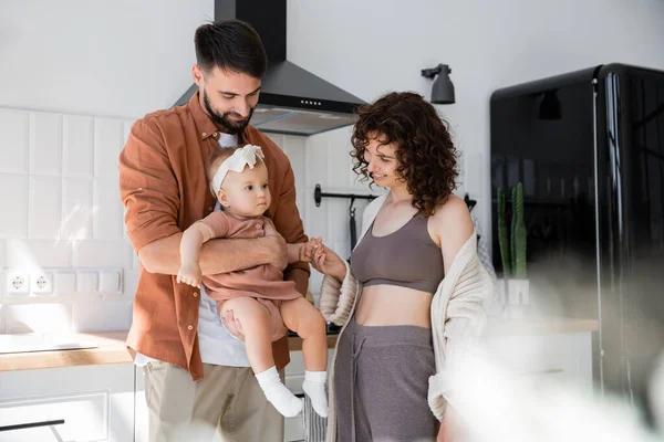 Complacido Barbudo Hombre Sosteniendo Brazos Hija Cerca Positiva Esposa Cocina — Foto de Stock