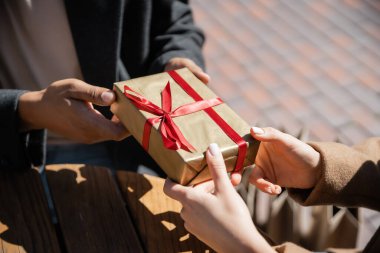 partial view of african american man giving new year present to woman outdoors clipart