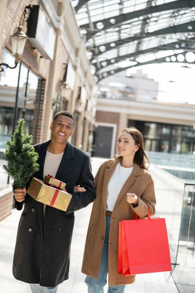 Gelukkig Trendy Interraciale Paar Met Kleine Kerstboom Presenteert Wazig Stedelijke — Stockfoto