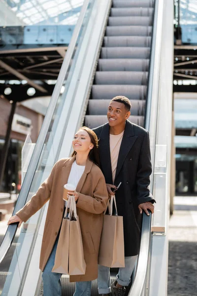 Elegante Casal Interracial Com Sacos Compras Sorrindo Olhando Para Longe — Fotografia de Stock