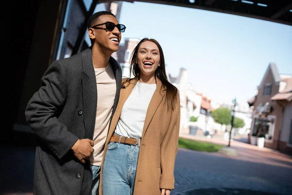 Cheerful Woman Trendy Coat Laughing African American Man Sunglasses Street — Stock Photo, Image