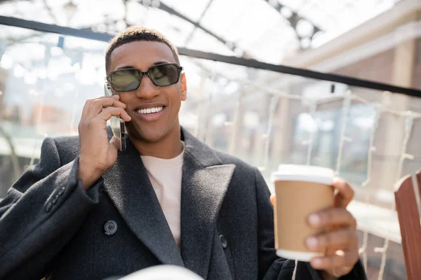 アフリカ系アメリカ人でコーヒーを飲みながらスマートフォンで会話をしていると — ストック写真