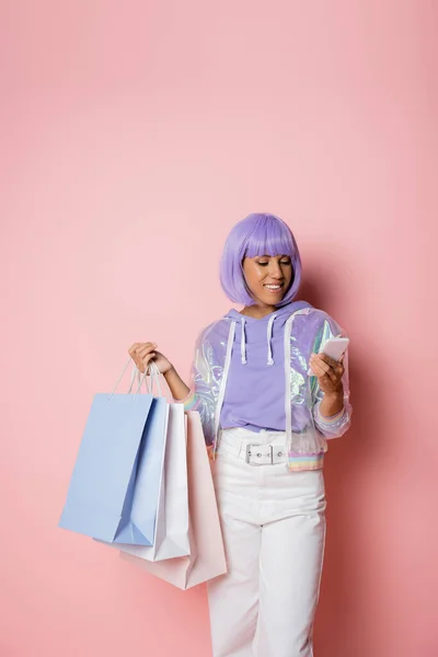 Mujer Afroamericana Complacida Peluca Púrpura Usando Teléfono Inteligente Sosteniendo Bolsas — Foto de Stock