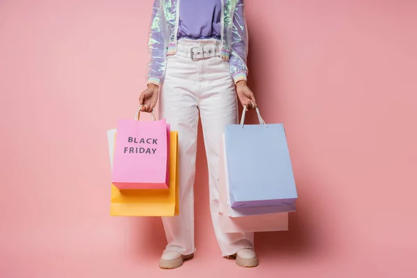 身穿透明夹克和白色裤子的女人拿着印有黑色星期五粉红字母的购物袋的剪影 — 图库照片