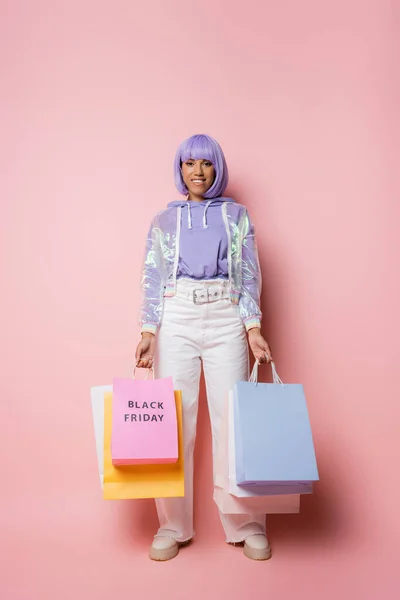 明るいアフリカ系アメリカ人女性紫の髪の女性ピンクの金曜日のレタリングとショッピングバッグを保持 — ストック写真