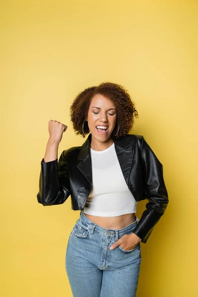 Mujer Afroamericana Emocionada Elegante Chaqueta Cuero Jeans Posando Amarillo —  Fotos de Stock