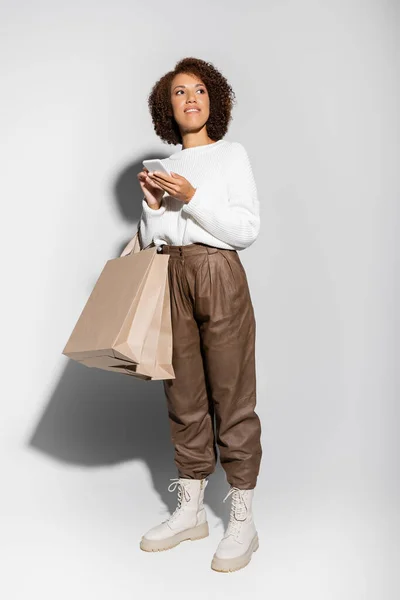 Güz Kıyafetli Elinde Alışveriş Poşetleri Olan Gri Üzerinde Akıllı Telefon — Stok fotoğraf