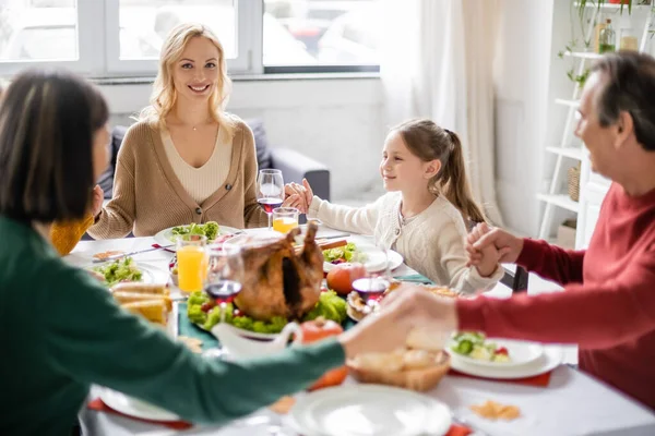 Mujer Sonriente Mirando Cámara Mientras Familia Toma Mano Cerca Cena — Foto de Stock