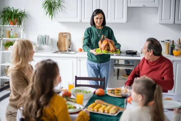 Abuelo Multiétnico Positivo Sosteniendo Sabroso Pavo Cerca Familia Borrosa Durante — Foto de Stock