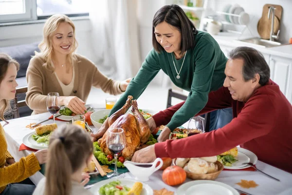 Multikulturell Kvinna Lägger Kalkon Bordet Nära Thanksgiving Middag Och Familj — Stockfoto