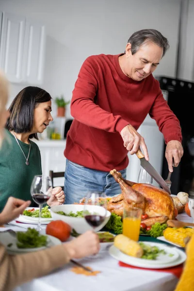 Senior Uomo Taglio Tacchino Vicino Interrazziale Famiglia Durante Ringraziamento Cena — Foto Stock