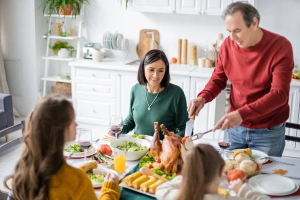 Abuelo Multiétnico Maduro Mirando Delicioso Pavo Cerca Familia Celebrando Acción — Foto de Stock