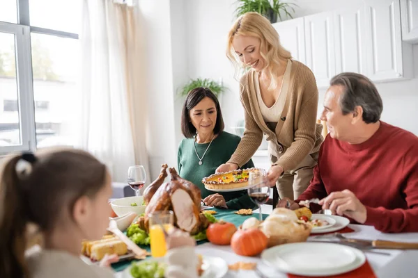 Mulher Positiva Segurando Torta Perto Pais Multiétnicos Jantar Ação Graças — Fotografia de Stock