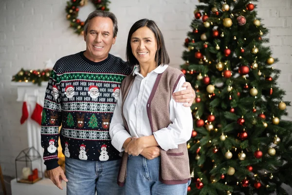 Sonriente Hombre Suéter Con Patrón Festivo Abrazando Esposa Multirracial Cerca — Foto de Stock