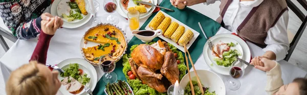 top view of family holding hands and praying near delicious thanksgiving dinner, banner
