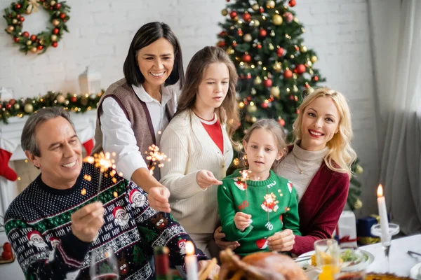 Cheerful Multicultural Family Holding Sparklers Festive Dinner Living Room Decorated — Stock Photo, Image